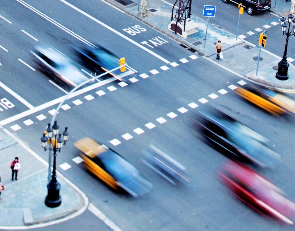 A bustling city intersection with cars in motion, emphasizing the fast pace of urban life. When buying a car from abroad, navigating vibrant cityscapes like this becomes part of the future the adventure.