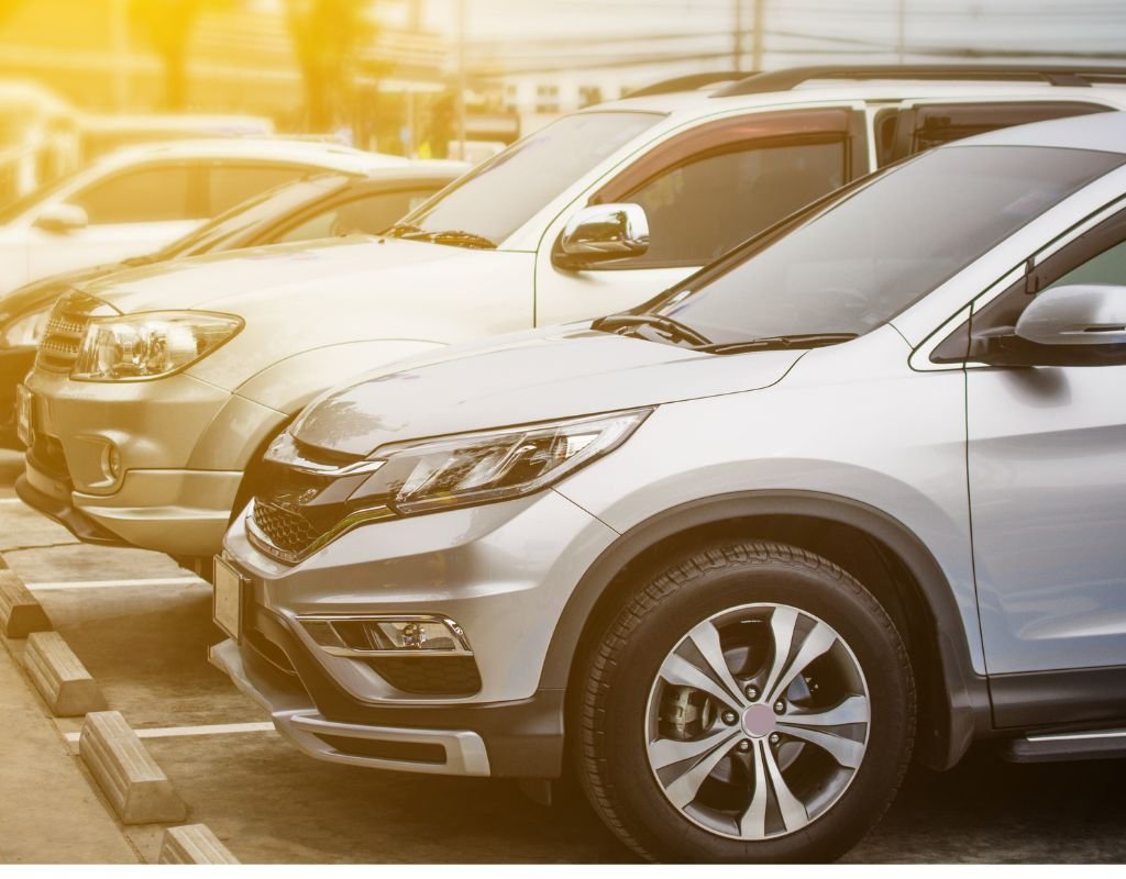 Rows of modern SUVs and sedans parked in a lot, illuminated by a warm sunset. Buying a car from abroad can provide access to unique models like these.