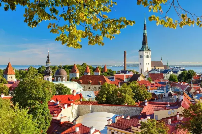 Estonia's beautiful red rooftops along the river's edge on a sunny day. This is one of the most recommended countries with digital nomad visas in Europe because of the low cost of living and high quality of life.