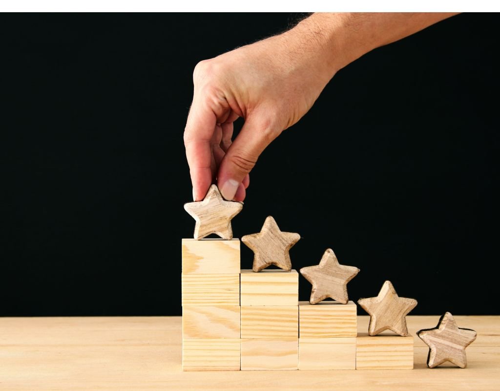 A hand places the final star atop a stack of wooden stars, symbolizing achievement and growth. For expats, choosing the best countries to move to often involves evaluating quality of life, like building a solid foundation.