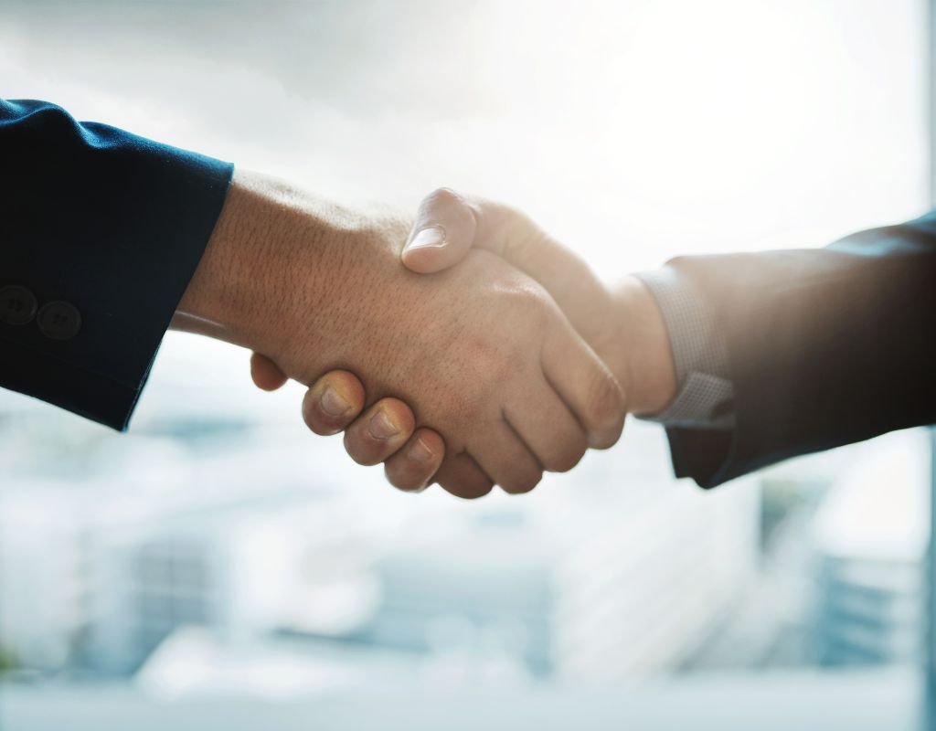 Two people in business suits shake hands, suggesting partnership or agreement. The best countries for expats are those with strong professional networks and welcoming business environments.