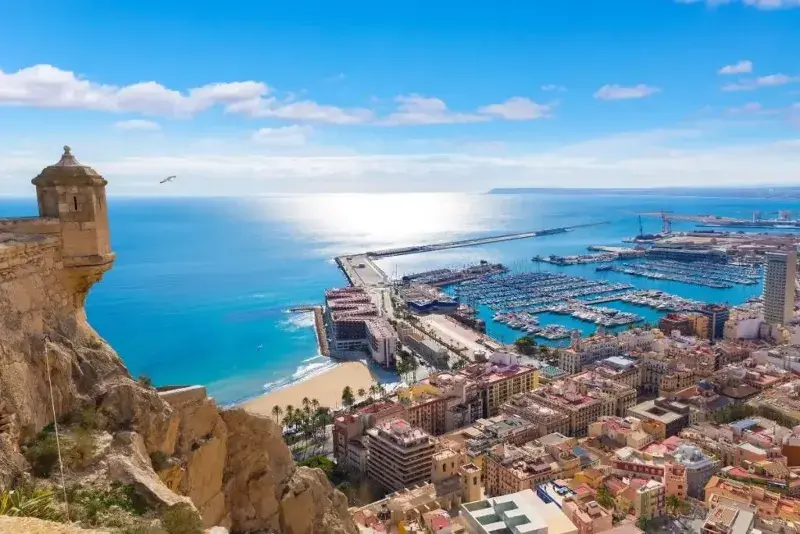 Alicante as seen from the cliffs towards the marina out on the turquoise Mediterranean water and the city on a sunny day.