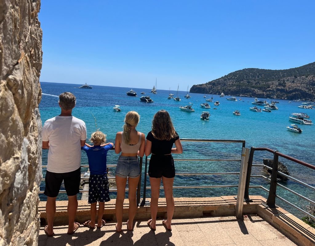 Colleen's family standing at the hand railing looking out on the bay full of boats floating the water on a sunny day.