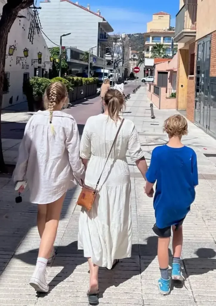 Mom, with her teenage daughter and her younger son walking on the streets of Costa Rica as seen from behind on a sunny day.