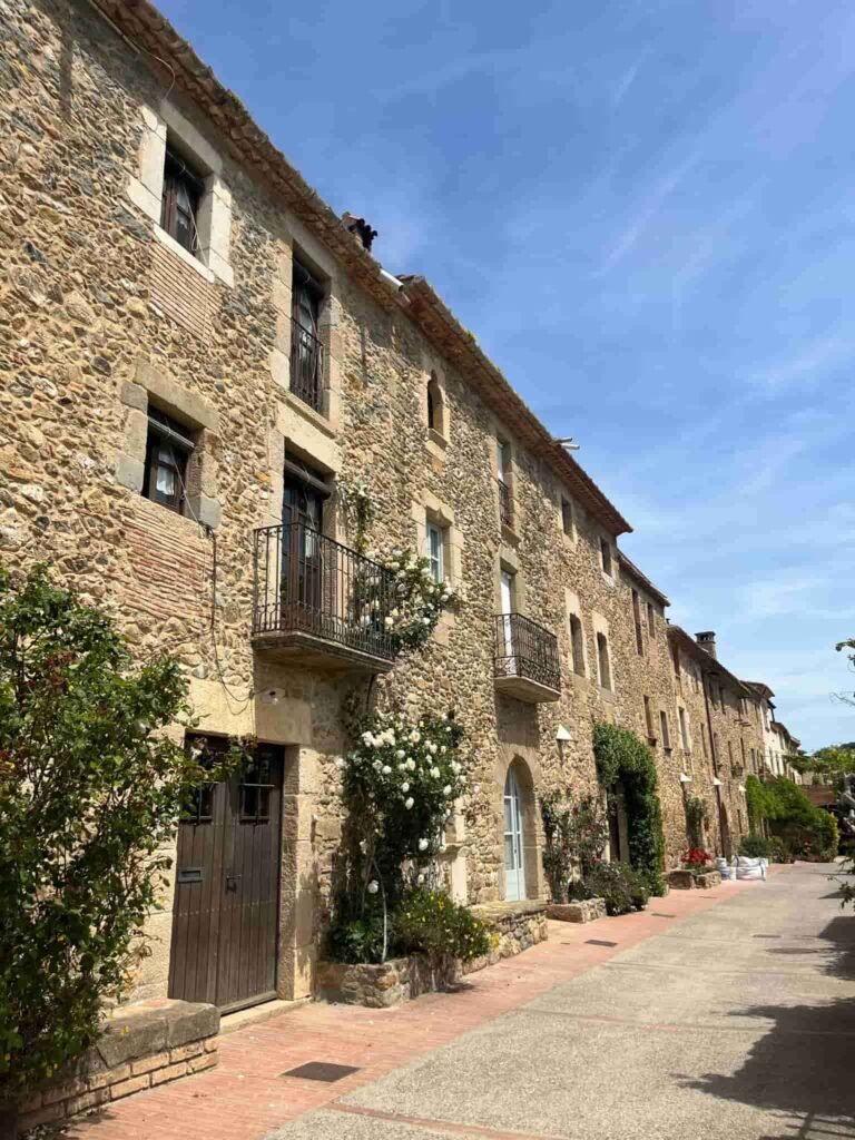 Street view of old restored stone homes with juliette balconies on a sunny day in Costa Brava.