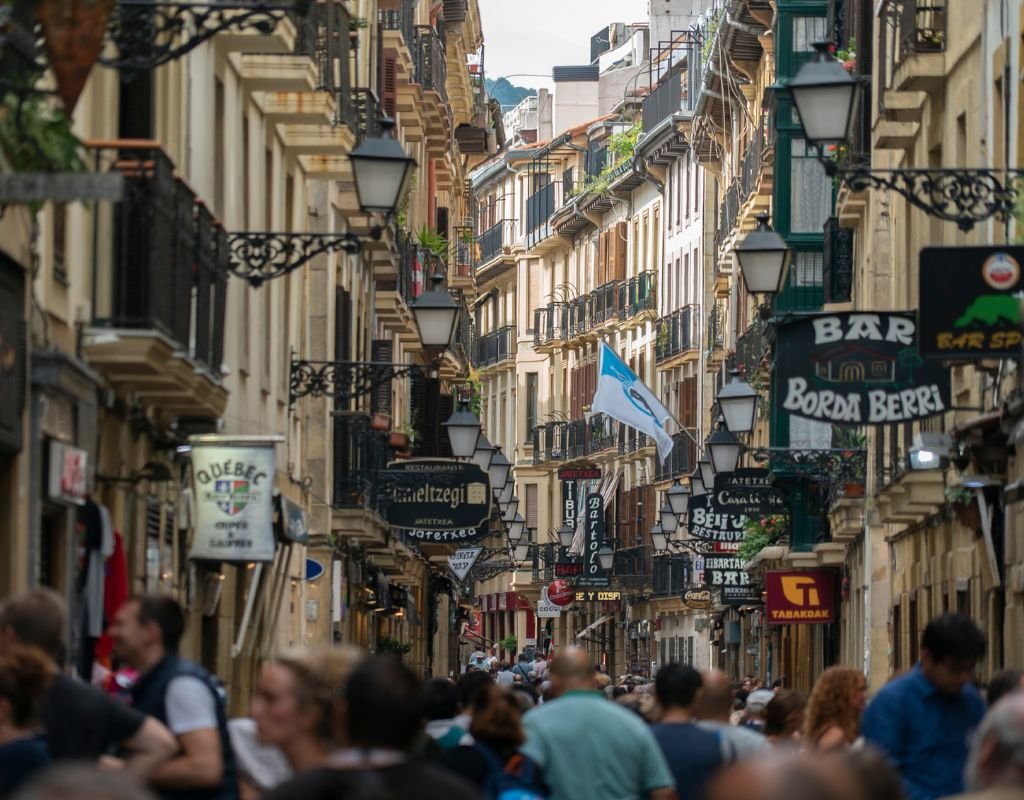 A lively street in the Old Town of San Sebastian, packed with bars, restaurants, and people enjoying pintxos under traditional wrought-iron balconies. A must-visit area filled with Basque charm.
