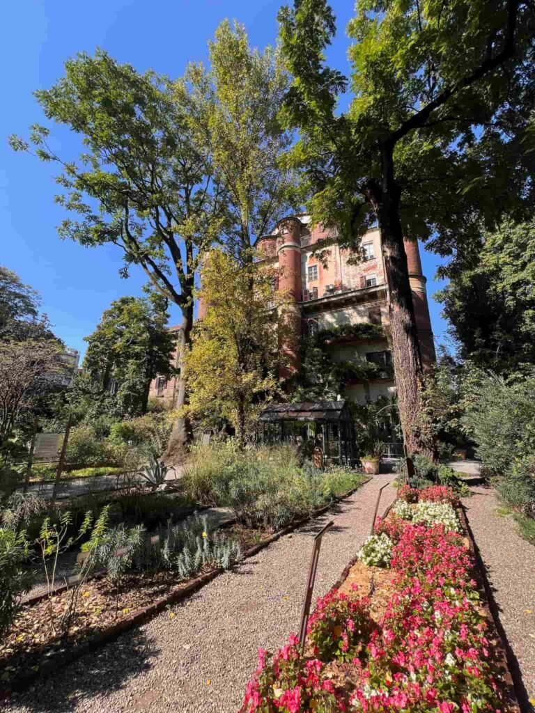 Closeup of the beautiful garden in front of a private home as seen hidden by the tall trees in front of it in Milan.