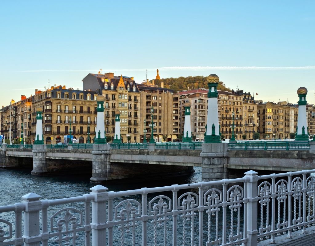 The grand Maria Cristina Bridge in San Sebastian, featuring elegant green and gold lampposts, with stately buildings lining the riverbank. A scenic area offering some of the best options for where to stay in San Sebastian.