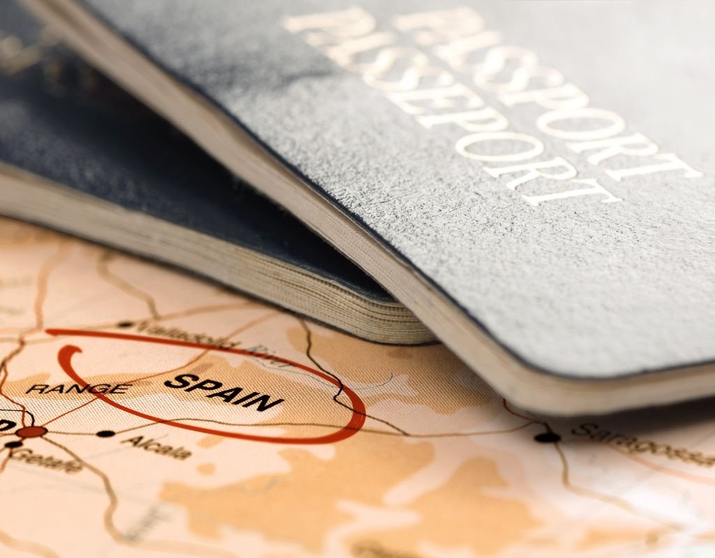 A map with Spain marked prominently in red alongside a stack of passports, symbolizing travel and citizenship considerations