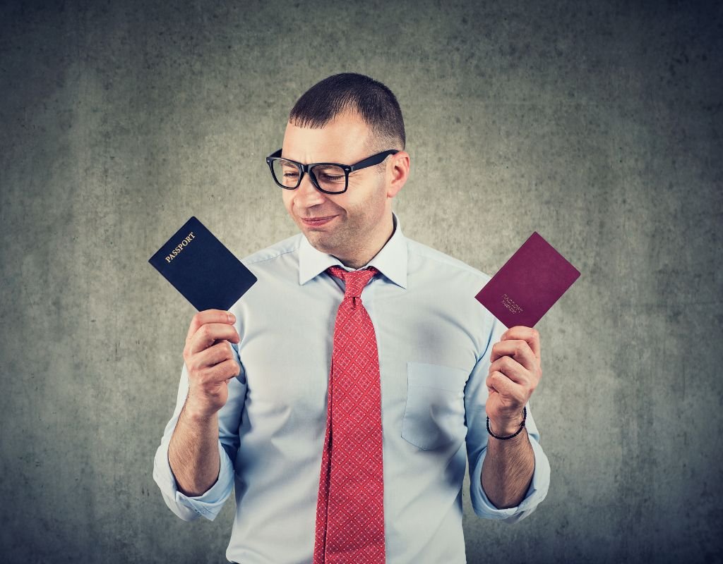 A man in glasses inspects two passports thoughtfully, symbolizing the choice of national identity. For Spanish citizenship, a formal application after consistent residency is required