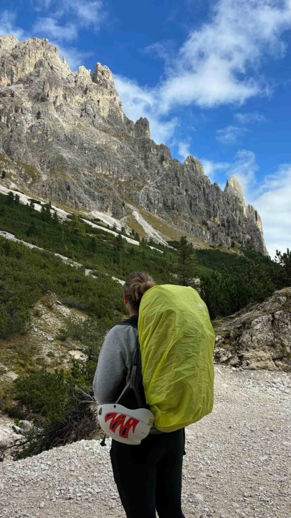 A man with huge green bag looking at Dolomites view.