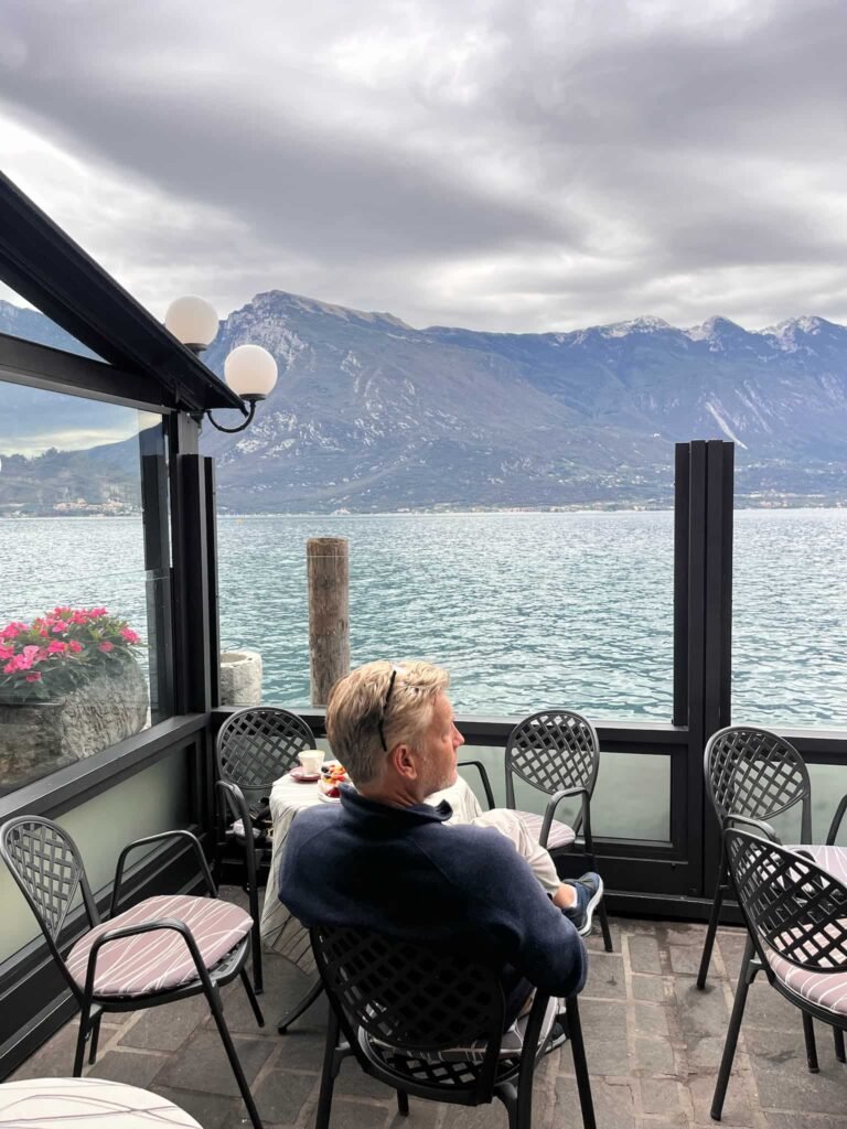 A man sitting in a balcony and view of the Lake Garda.