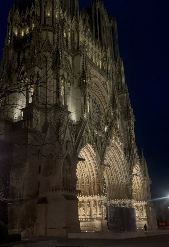 The façade of a majestic Gothic cathedral illuminated at night, highlighting its towering spires and intricate stonework. This breathtaking view is a reminder of France’s deep history and cultural richness.