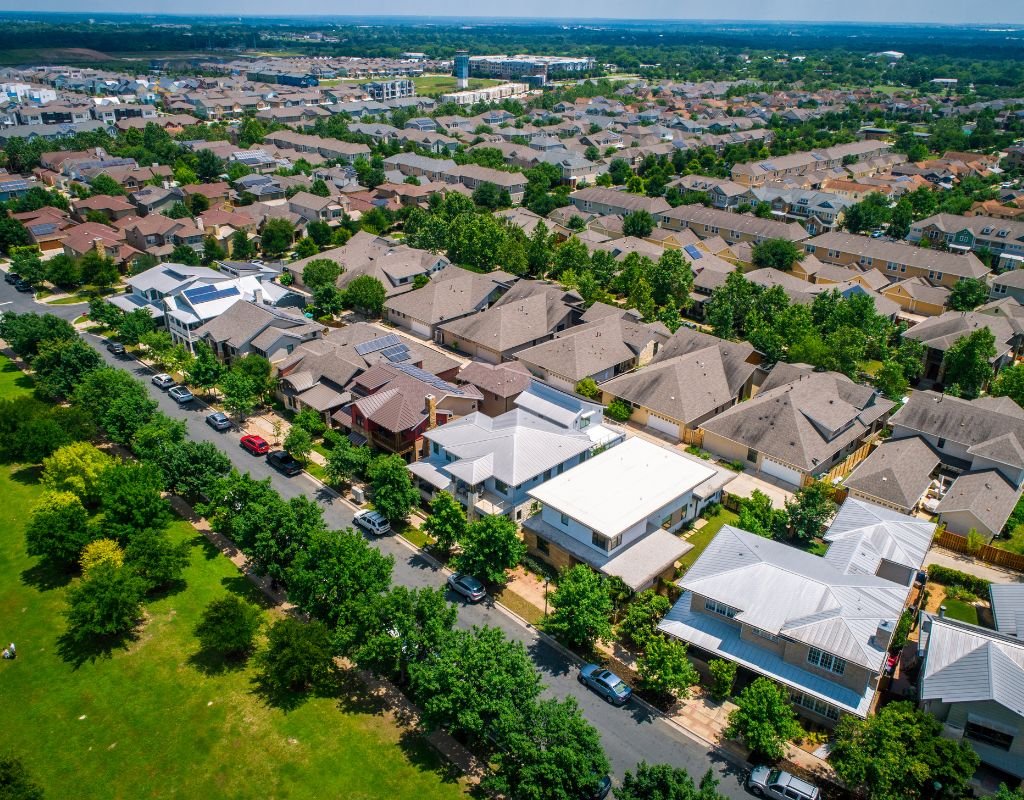 Aerial view of a suburban neighborhood with rows of houses and tree-lined streets