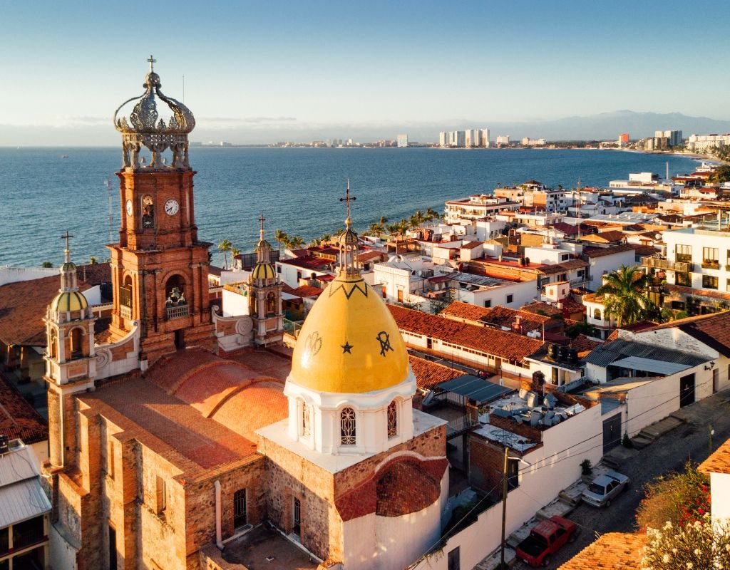 A beautiful colonial church framed by the sea and cityscape, showcasing Mexico’s blend of history and modernity.